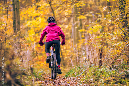 nice senior woman riding her mountainbike on the autumnal forest trails near Stuttgart, beautiful warm colors