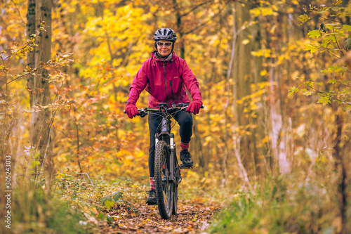 nice senior woman riding her mountainbike on the autumnal forest trails near Stuttgart, beautiful warm colors