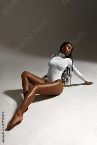 African woman portrait in white underwear on dark background. Fashion beauty girl model in lingerie in studio