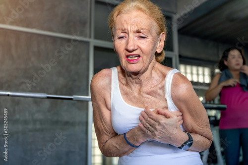 Senior woman Caucasian heart attack during training at fitness gym.