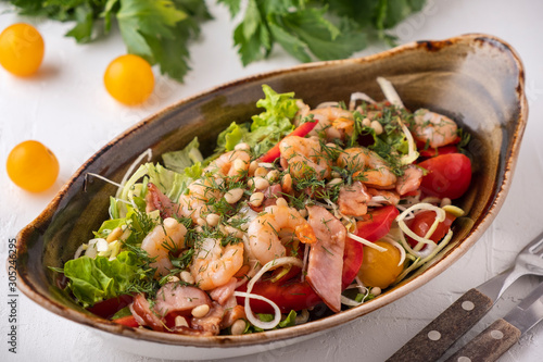 Delicious shrimps salad with fried bacon, vegetables and pine nuts. Tasty seafood salad.