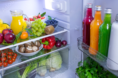 Food photography of a clean fridge filled with vegan foods such as fruits vegetables, juices and plant milk