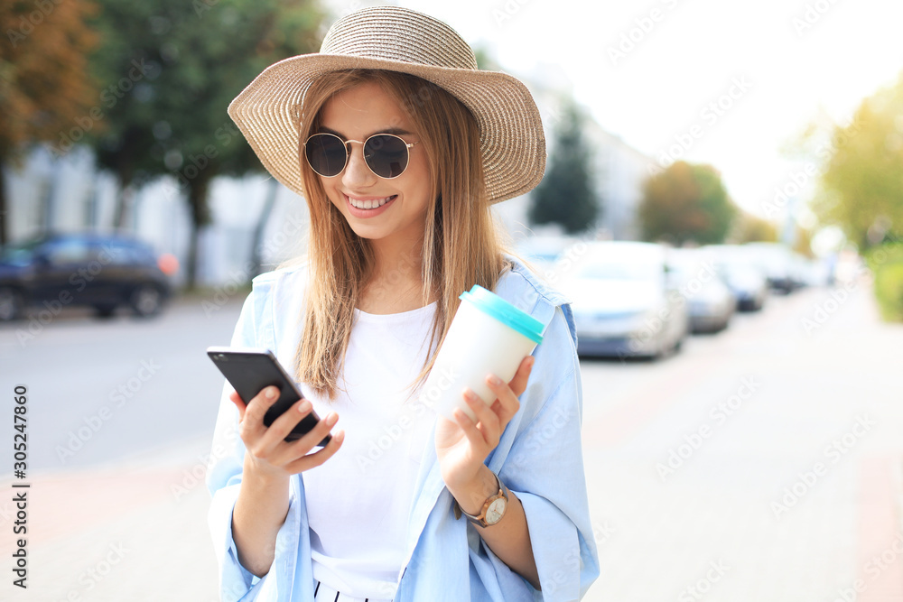 Beautiful young blonde girl using mobile phone while standing outdoors.