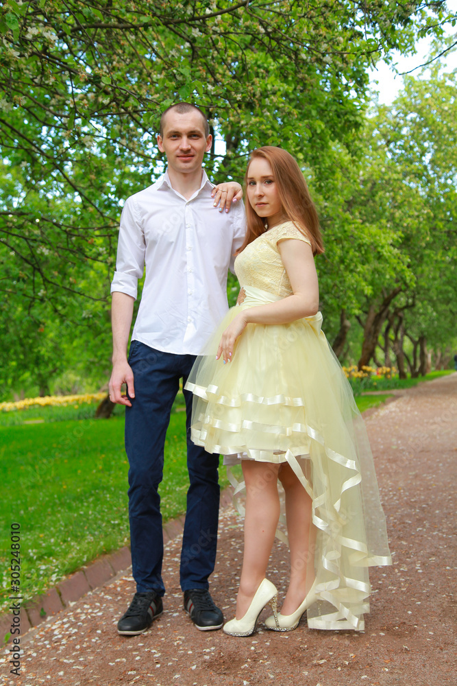 The bride and groom are walking in the apple orchard, posing under the branches of an apple-tree. The bride and groom are walking in the apple orchard, posing under the branches of an apple-tree.