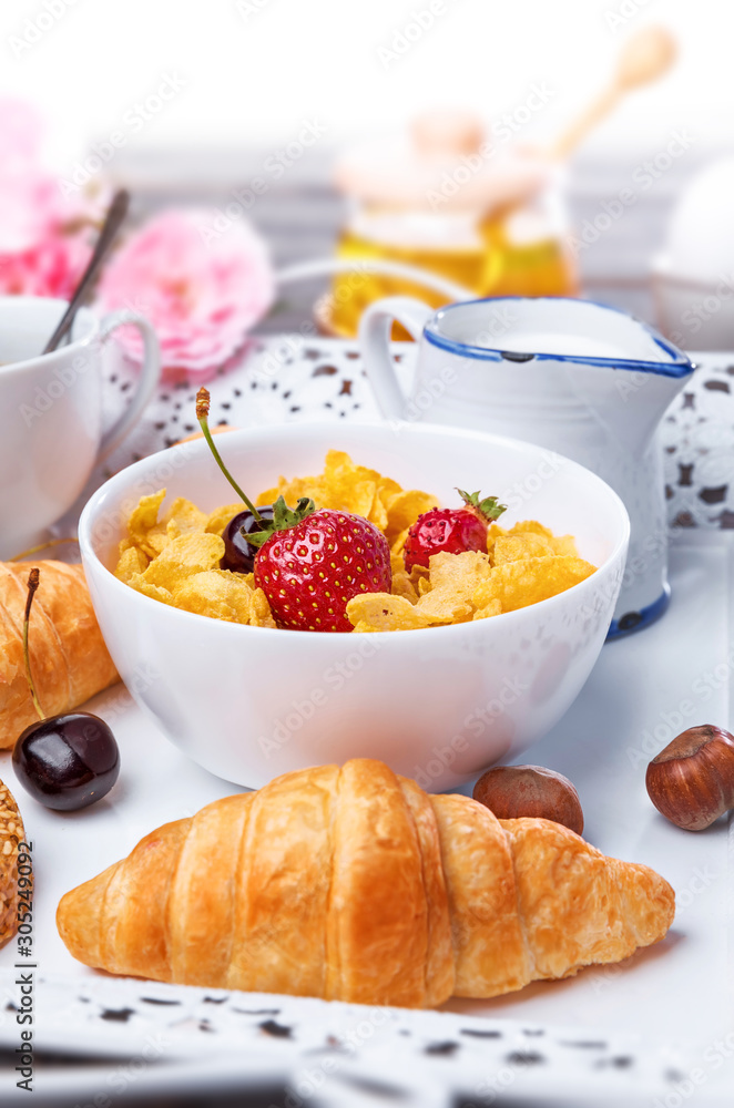 Breakfast with cornflakes berry honey and croissant on wooden board white tray. Breakfast with cornflakes berry honey and croissant on wooden board white tray.