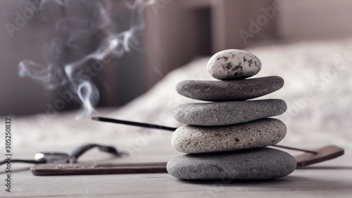 Concept of relax or meditation. Pyramid of zen stones, burning incense stick, bedroom interior. photo