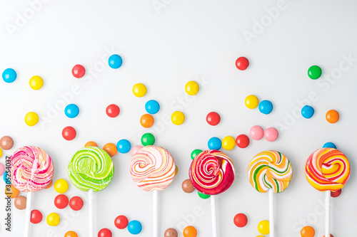 multi-colored chocolate tablets and caramel candies on a stick lie beautifully on a light background, top view