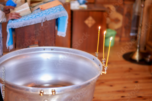 a container with water and candles for the baptism of children. the process of baptizing a child.