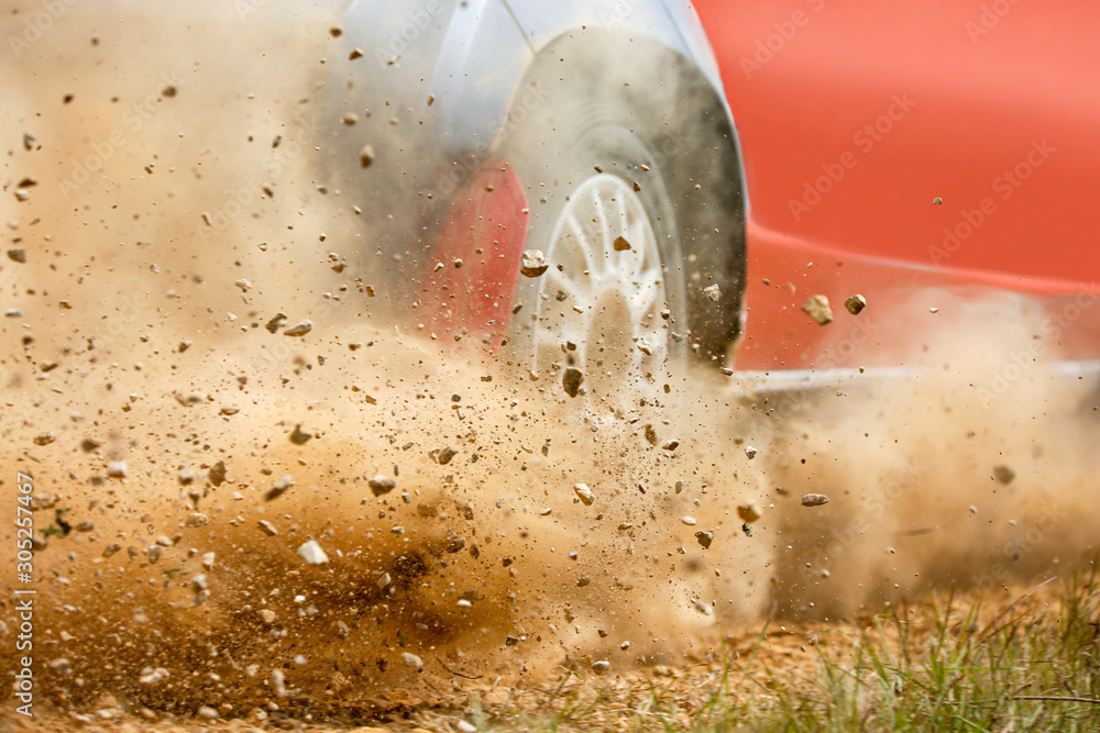 Gravel splashing from rally race car drift on track.