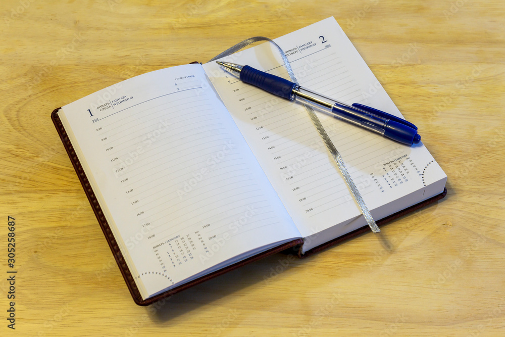 Russian-English datebook and pen lying on the surface of the table. The datebook is open on the first of January. Russia. Russian-English datebook and pen lying on the surface of the table. The datebook is open on the first of January. Russia.