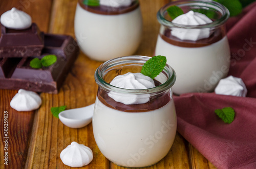 Traditional Italian dessert panna cotta with chocolate sauce and crispy meringue, dessert for Valentine's Day served in glass jars.