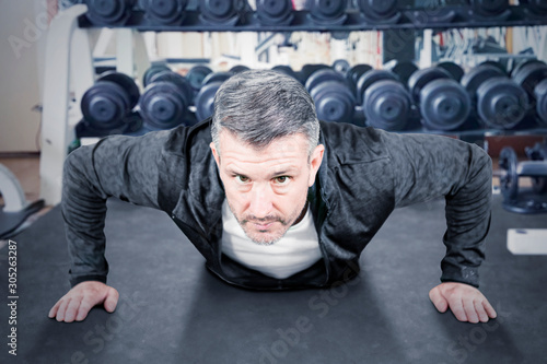 Matured man doing push-ups in weight room
