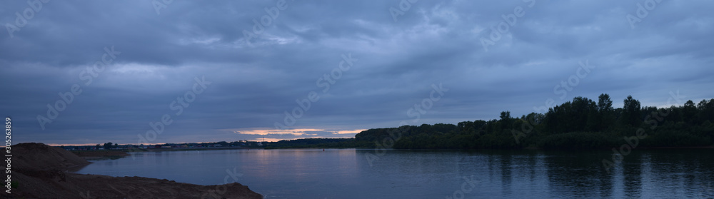 Summer evening on the river. Panoramic image of the water surface in the natural environment, late in the day. Summer evening on the river. Panoramic image of the water surface in the natural environment, late in the day.