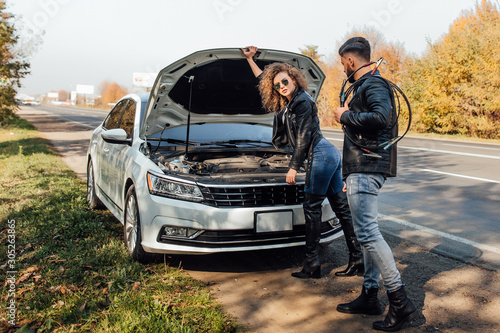 The young woman broke down the white car while traveling on the way to rest, bearded strong man help her on road. © Тарас Нагирняк