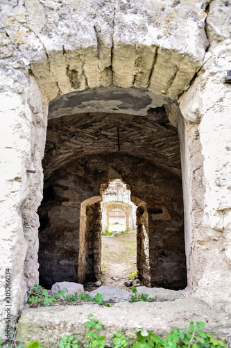 Dilapidated ancient synagogue. View of the old structure through the arched window. The texture of the old dilapidated masonry. Green vegetation. Rashkov  Moldova.