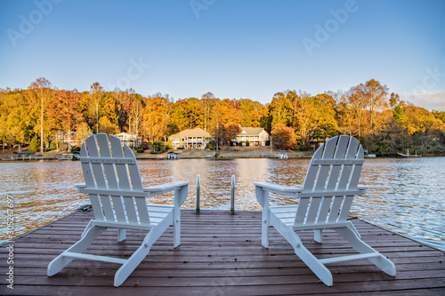 Adirondack style chairs on a dock, overlooking a beautiful, quiet, lake. Concept of a relaxing vacation in a remote area.