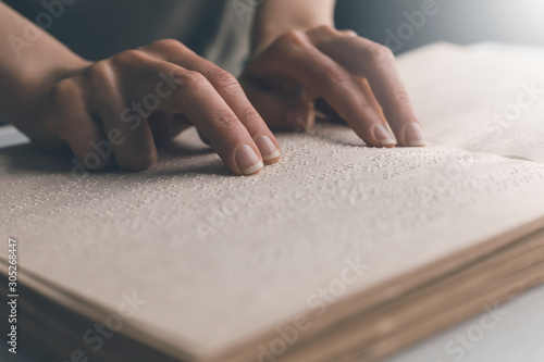 The hand of a blind man reads the text of a braille book. photo