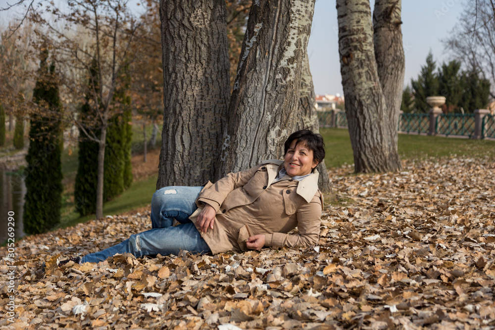 happy and cheerful woman on autumn leaves in the park