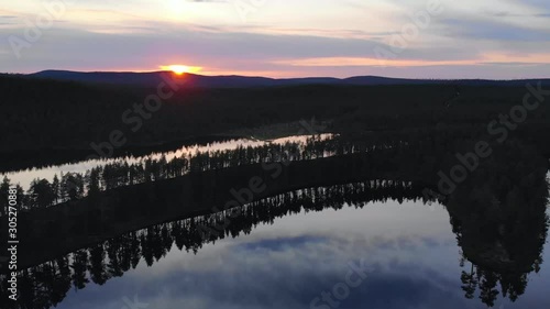 Aerial, rising, drone shot, overlooking a esker, at lake Helanderin Kotajarvi, midnight sun, in Urho Kekkonen national park, at sunset, on a summer evening, in Lapland, Finland photo