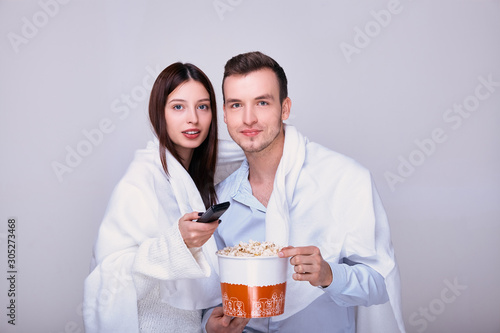 Man and woman watching tv and eating popcorn snack.