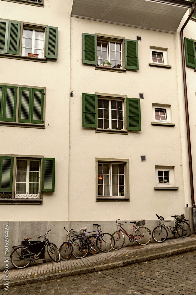 Many bicycles near the wall of the old house