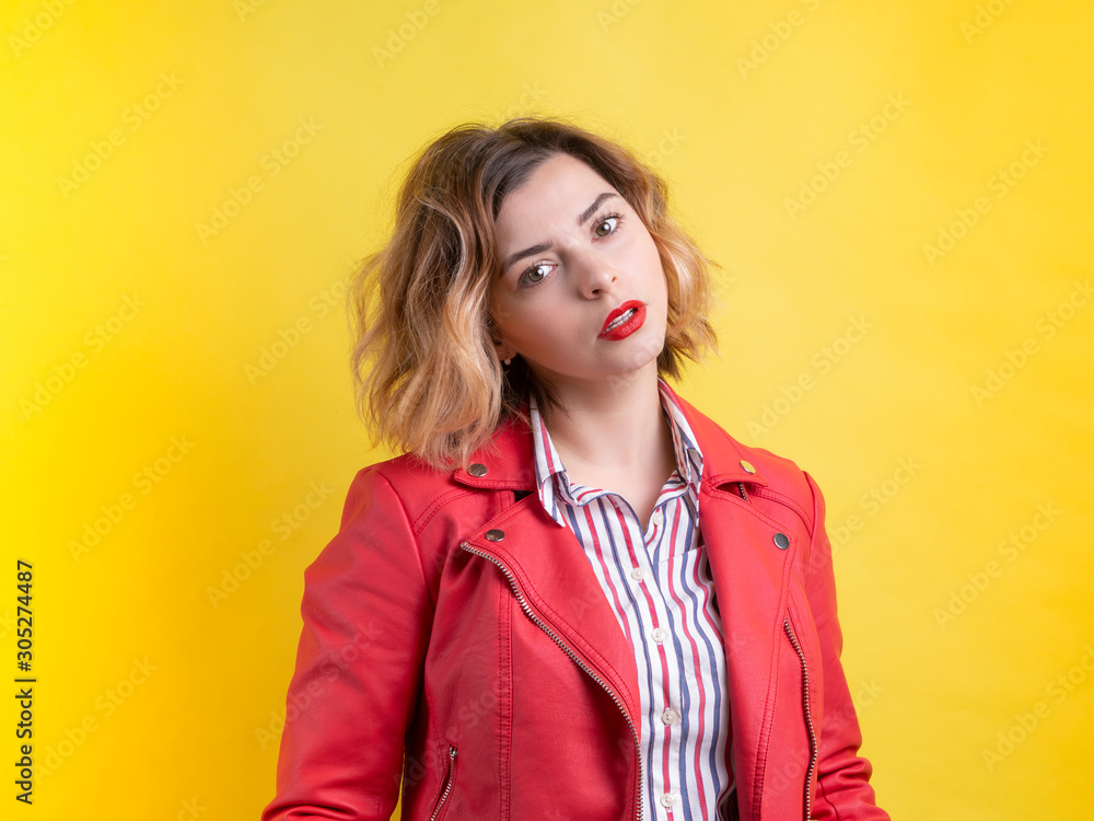 Top model hot girl with red lipstick in a red leather jacket with her head bowed on a yellow background. In a pose of flirting. Dating site ad concept Top model hot girl with red lipstick in a red leather jacket with her head bowed on a yellow background. In a pose of flirting. Dating site ad concept