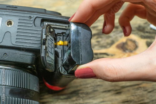 A photographer changes the battery in his SLR camera while shooting in the Studio. focus on the camera battery