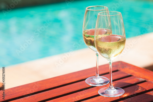 Elegant flute glass of sparkling white wine or champagne by side of swimming pool