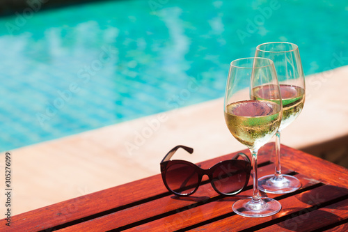 Elegant flute glass of sparkling white wine or champagne by side of swimming pool