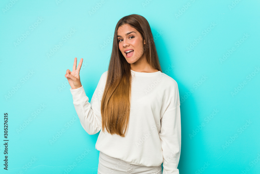Young slim woman joyful and carefree showing a peace symbol with fingers. Young slim woman joyful and carefree showing a peace symbol with fingers.