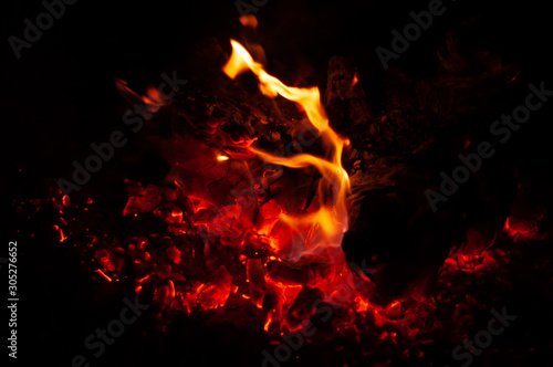 Fiery red coals in dying bonfire at dark night.