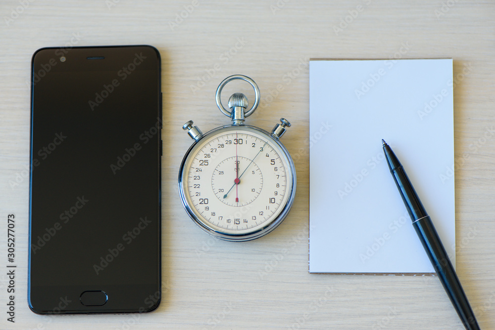 Notepad And Stopwatch biege desk table background Notepad And Stopwatch biege desk table background