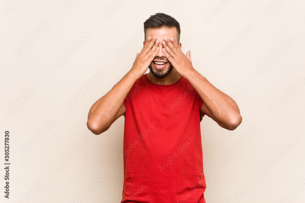 Young south-asian man covers eyes with hands, smiles broadly waiting for a surprise. Young south-asian man covers eyes with hands, smiles broadly waiting for a surprise.