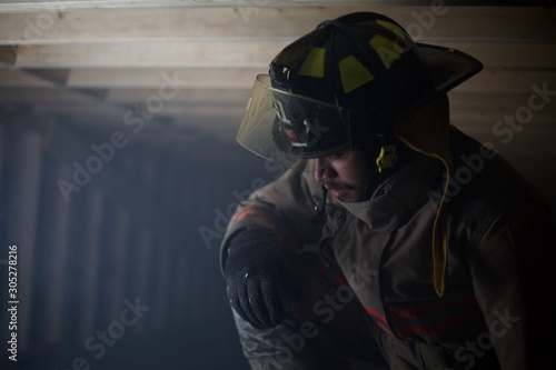 Fire Fighter kneeling down in wooden structure filled with smoke