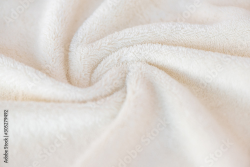 White delicate soft background of plush fabric plaid. Texture of beige soft fleecy blanket textile with twisted folds photo
