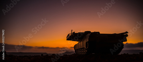 War Concept. Armored vehicle silhouette fighting scene on war fog sky background. American tank at sunset. © zef art