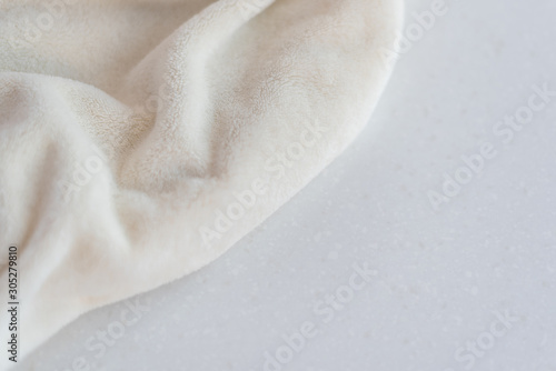 Soft cozy plush fabric with pile lies in beautiful folds on white marble countertop background. Delicate mock up.
