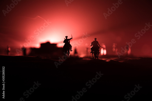 World war officer (or warrior) rider on horse with a sword ready to fight and soldiers on a dark foggy toned background. Battle scene battlefield of fighting soldiers.