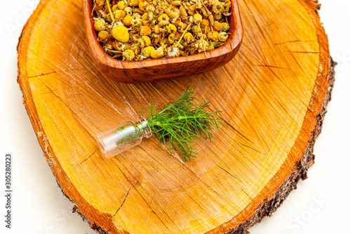 Chamomile with dry chamomile on wooden backgropund. Midern apothecary photo