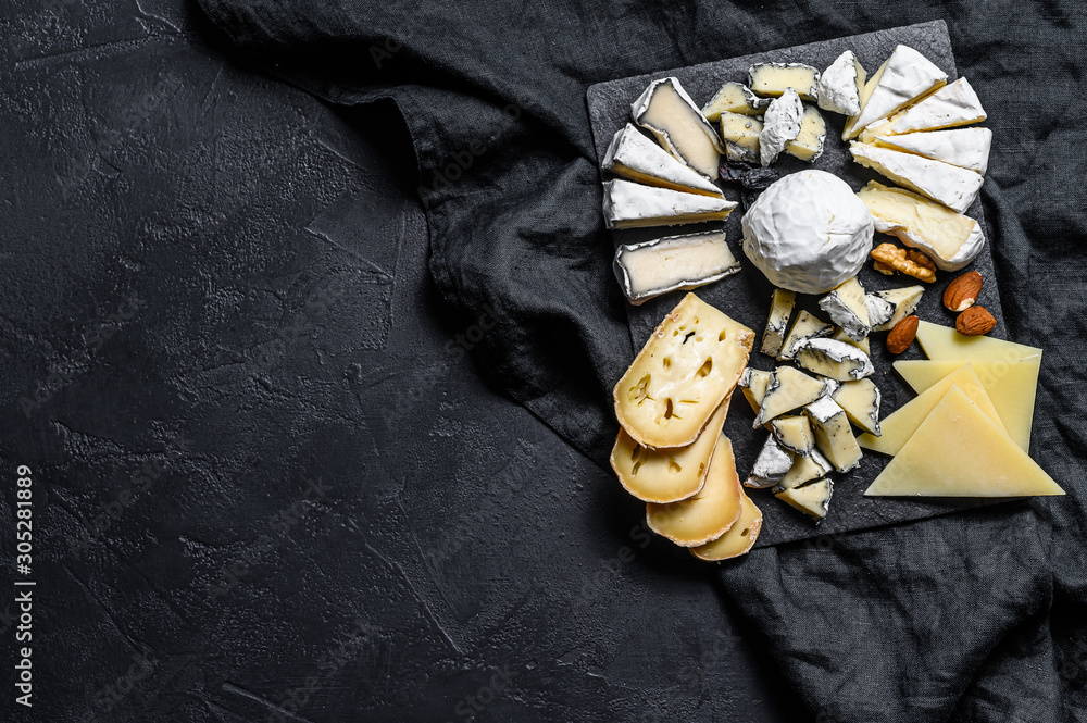 Cheese plate served with nuts and figs. Black background. Top view. Space for text