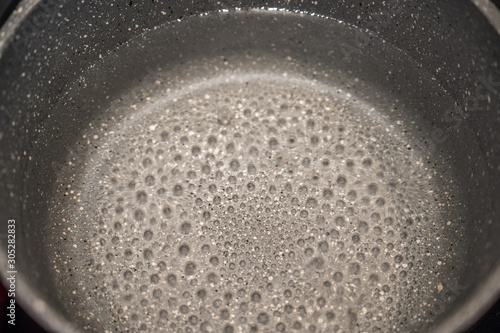 Kochendes Wasser in einem Kochtopf mit Antihaftbeschichtung als Hintergrund oder Textur