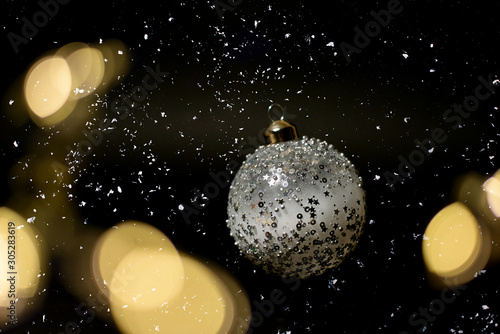 Fototapeta Naklejka Na Ścianę i Meble -  Christmas silver ball with stars and bokeh blurred sparkles and snow on black background.