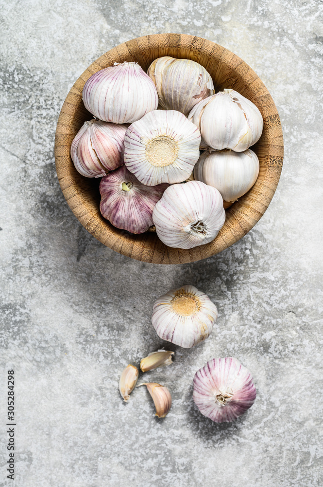 Garlic Cloves and Bulb in vintage wooden bowl. Gray background. Top view