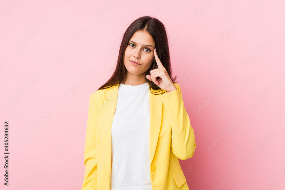 Young business woman pointing temple with finger, thinking, focused on a task. Young business woman pointing temple with finger, thinking, focused on a task.