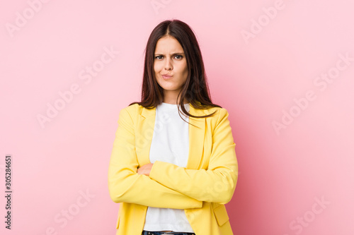 Young business woman frowning face in displeasure, keeps arms folded.