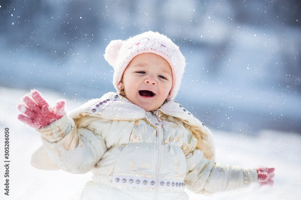 Little girl in white jacket having fun, playing outside, surrounded with snow. Little girl in white jacket having fun, playing outside, surrounded with snow.