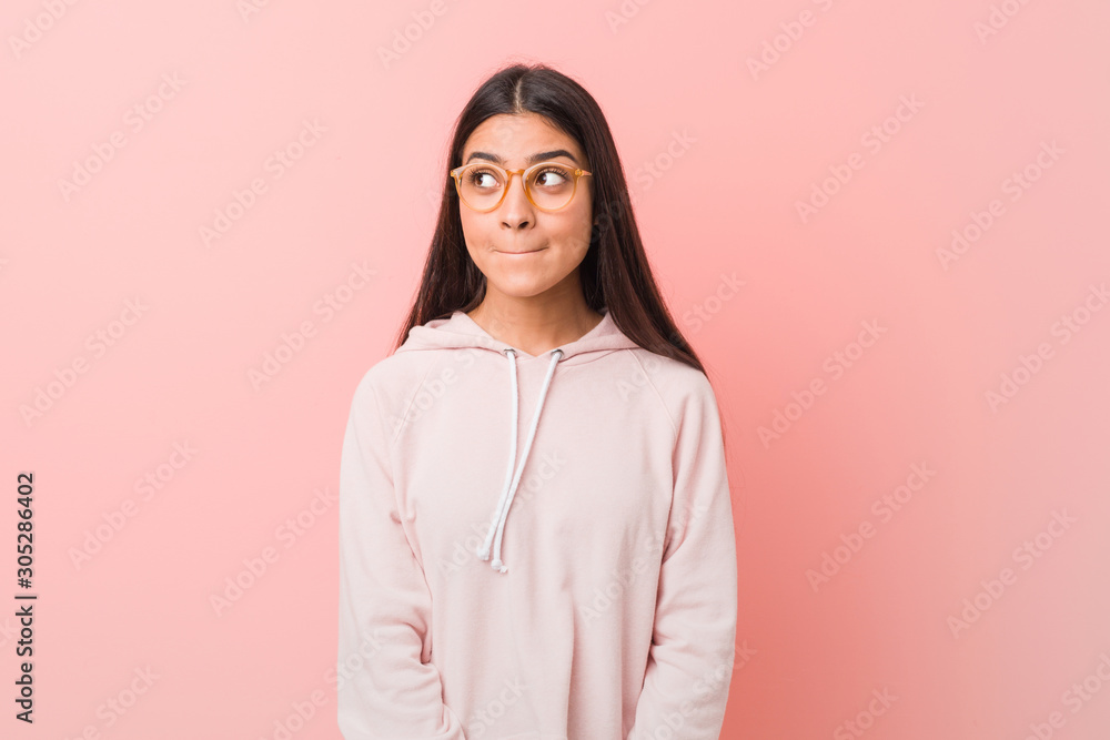 Young pretty arab woman wearing a casual sport look confused, feels doubtful and unsure. Young pretty arab woman wearing a casual sport look confused, feels doubtful and unsure.