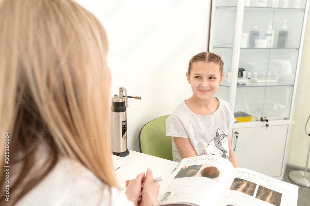 Young woman doctor in a white coat advises a teenager in a bright medical office