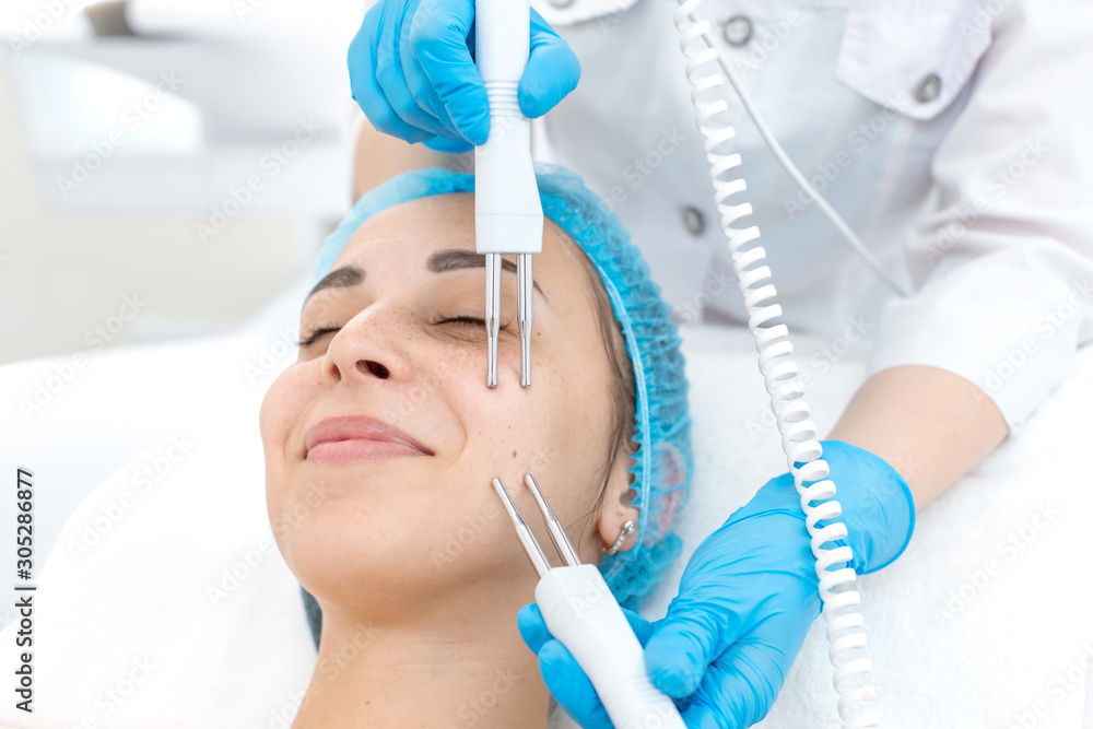 Portrait of a young beautiful girl face microcurrent therapy procedure. Facial care and rejuvenation. Increase epidermal tone Portrait of a young beautiful girl face microcurrent therapy procedure. Facial care and rejuvenation. Increase epidermal tone