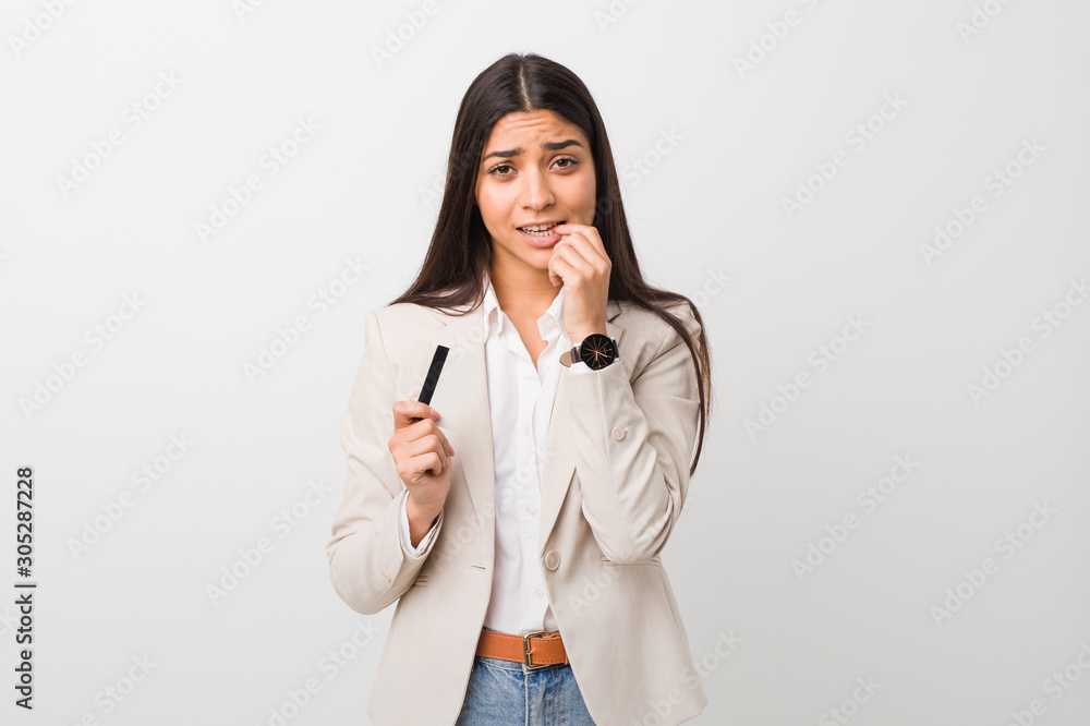 Young arab woman holding a credit card biting fingernails, nervous and very anxious. Young arab woman holding a credit card biting fingernails, nervous and very anxious.